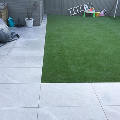 New porcelain patio installed in Guernsey garden with artificial grass.